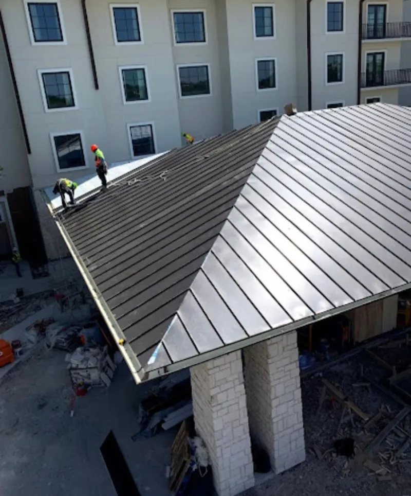 Crew installing standing seam metal roof panels on a commercial project in Lexington